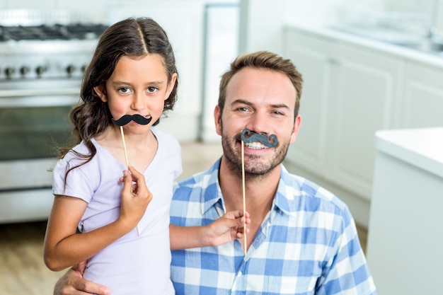 Foto padre e figlia con i baffi artificiali a casa