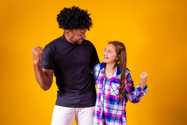 Father and daughter on yellow background celebrating victory Father and daughter making yes sign