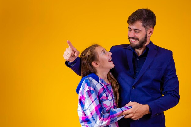 Father and daughter on yellow background with space for text father points to the horizon showing something to his daughter