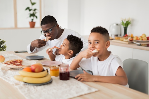 Padre che mangia pizza con i suoi figli