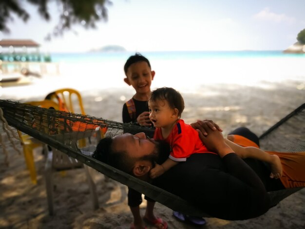 Photo father embracing daughter by siblings at beach