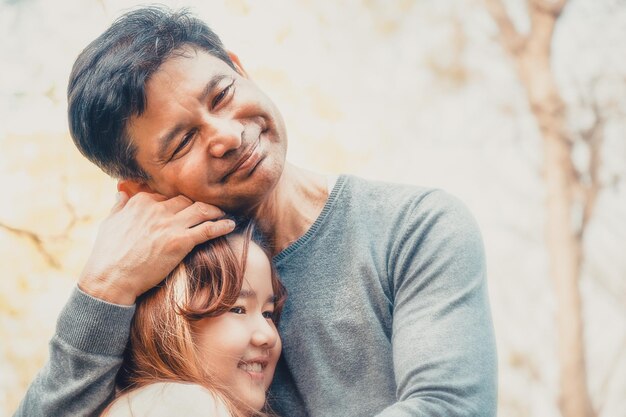 Photo father embracing daughter while standing against trees