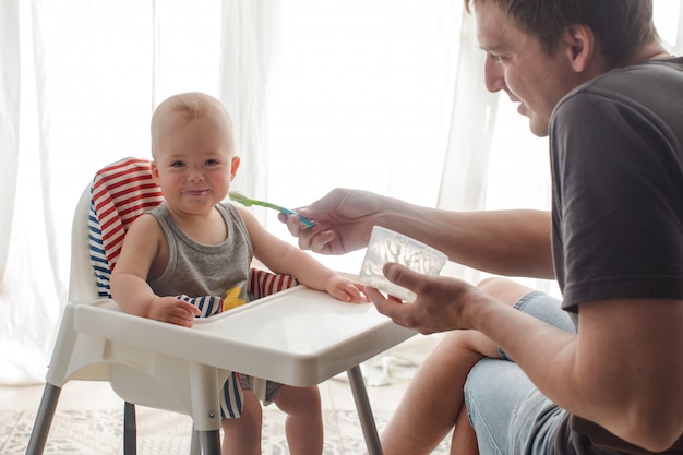 Father feeding cute baby at home