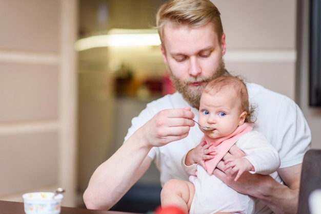 father feeding his child with fruit puree from a spoon