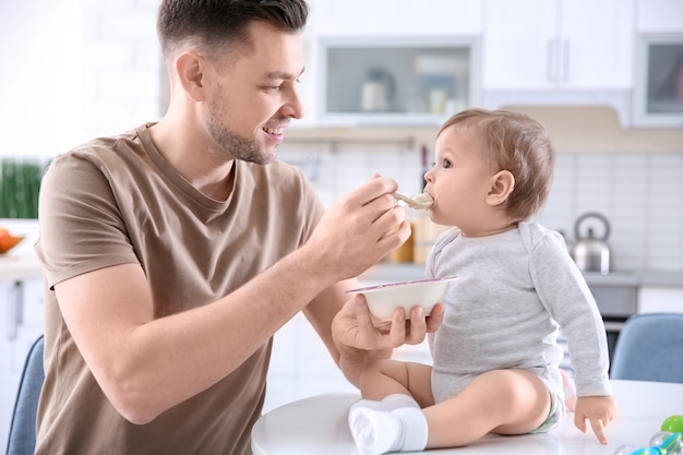Отец кормит своего маленького сына на кухне
