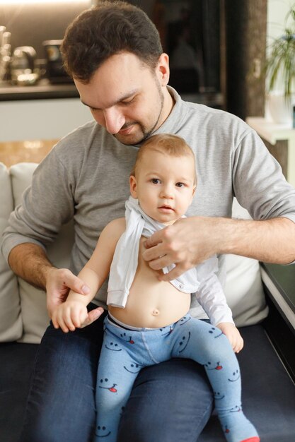 Photo father getting son dressed at home