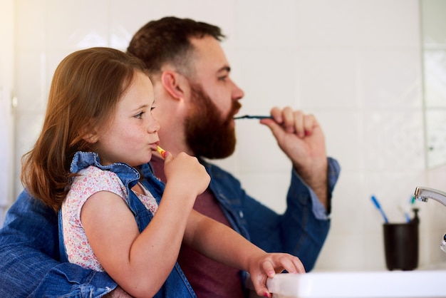 father girl and brush teeth in mirror for family hygiene in bathroom at home bonding and parenting health dad and child for dental care in basin to get rid of bacteria germs and toothbrush
