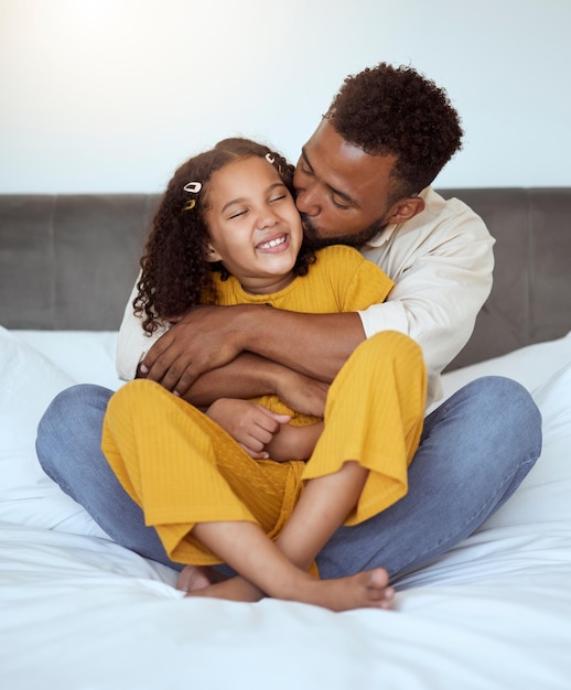 Father girl and family kiss with a hug on a bedroom bed spending quality time together Morning love and care of a dad and child in a home bonding and caring at a house with a happy smile