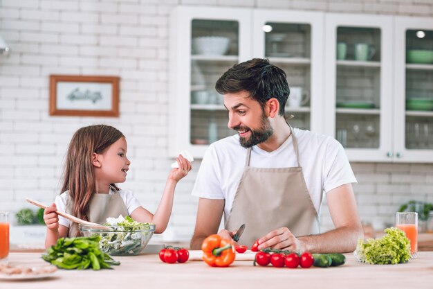 Father and girl spending time together on the kitchen preparing salad