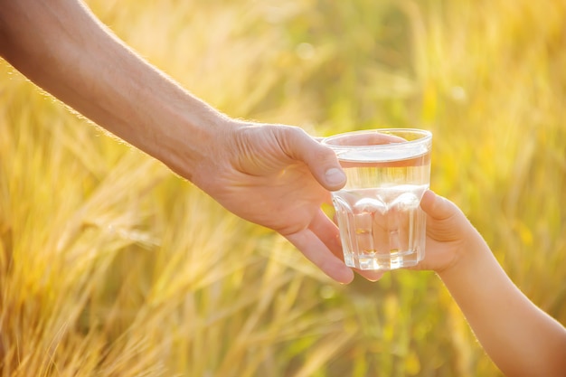 The father gives the child a glass of water. Selective focus.