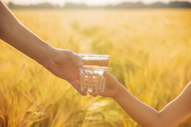 父親は子供にコップ一杯の水を与えます。セレクティブフォーカス