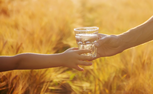 The father gives the child a glass of water. Selective focus.