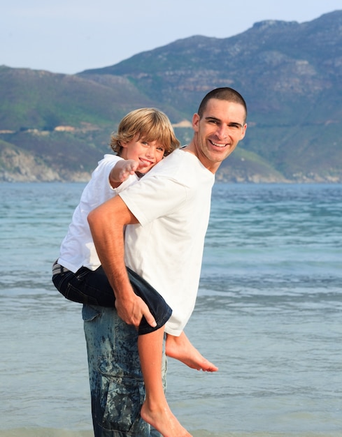 Padre dando figlio cavalluccio sulla spiaggia