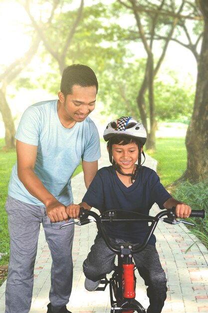 Father guides his son to ride a bicycle