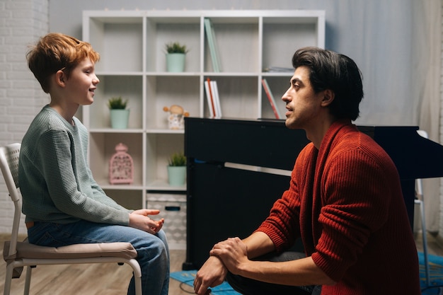 Father having conversation with yearold son by looking him in eye at home