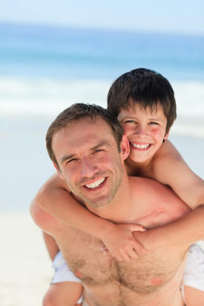 Father having son a piggyback on the beach