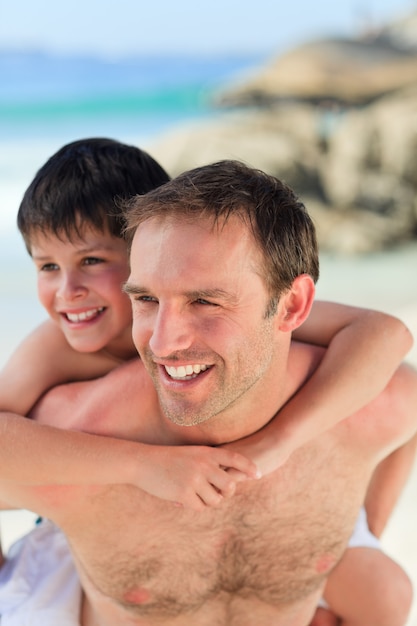 Father having son a piggyback on the beach