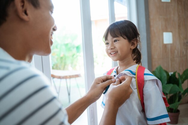 Father help her toddler kid preparing for school in the morning