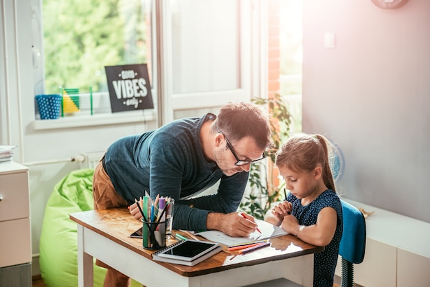 Father helping daughter to finish homework