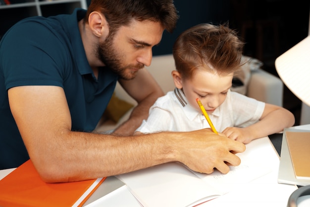 Foto padre che aiuta il suo piccolo figlio a fare i compiti a scuola