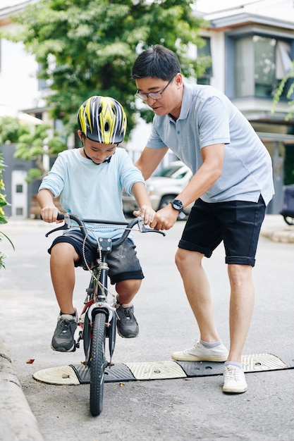 Padre che aiuta il figlio preadolescente che va in bicicletta per la prima volta