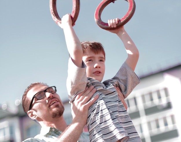 Father helps his son to catch up on the bar