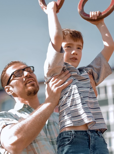 Father helps his son to catch up on the bar