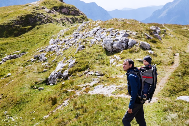 Father hiking with child in carrier backback in mountains Family on trekking day in the mountains