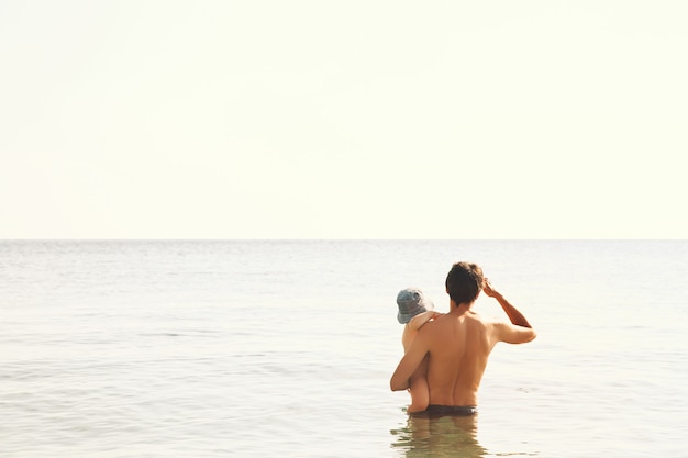 Father in his arms with son bathe in the sea or lake