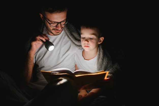 아버지와 그의 어린 아들이 집에서 취침 시간 이야기를 읽고 있다