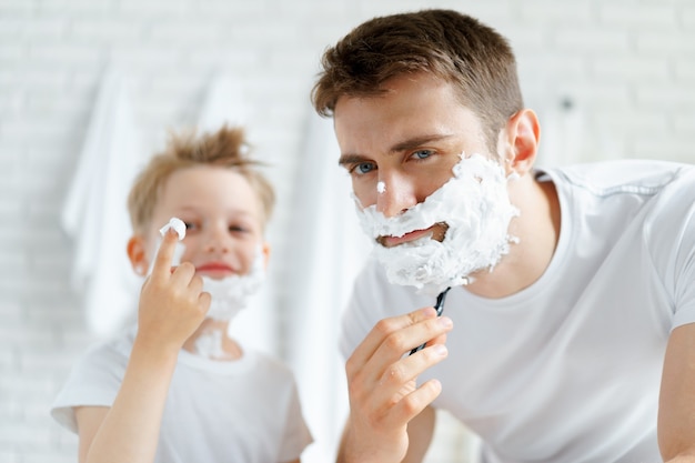 Father and his little son shaving together in bathroom