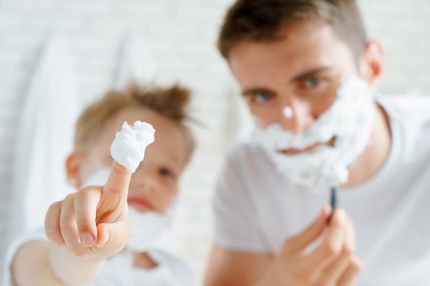 Father and his little son shaving together in bathroom