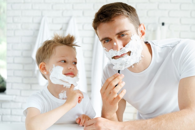 Father and his little son shaving together in bathroom