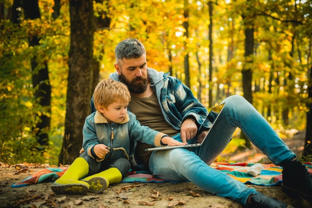 Father and his toddler son walking during the hiking activities in autumn forest active family time ...