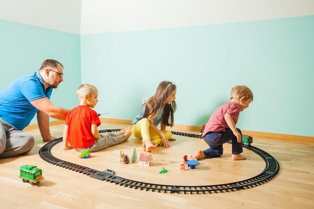 Father and his two sons and a daughter play with the toy railway