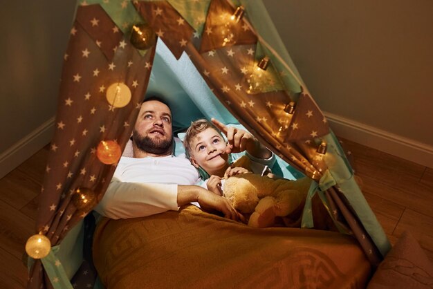 Father and his young young lying down together inside of tent