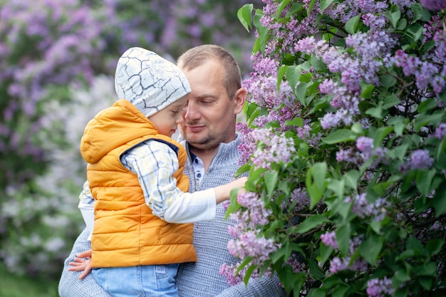 Отец обнимает милого маленького сына, папа и маленький ребенок обнимаются, обнимаясь, наслаждаясь временем вместе на летней природе. Концепция отцовства.