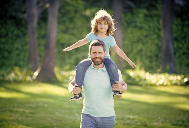 Father hold his son outdoor happy fathers day happy family dad and kid boy spend time together child sit on daddys shoulders childhood and fatherhood togetherness family values