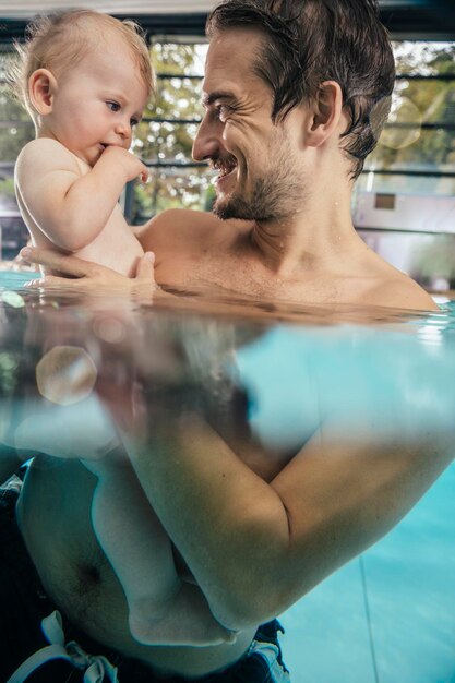 Father holding baby in indoor swimming pool