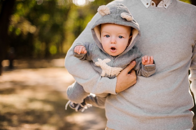 Padre che tiene un figlio carino bambino sotto il braccio