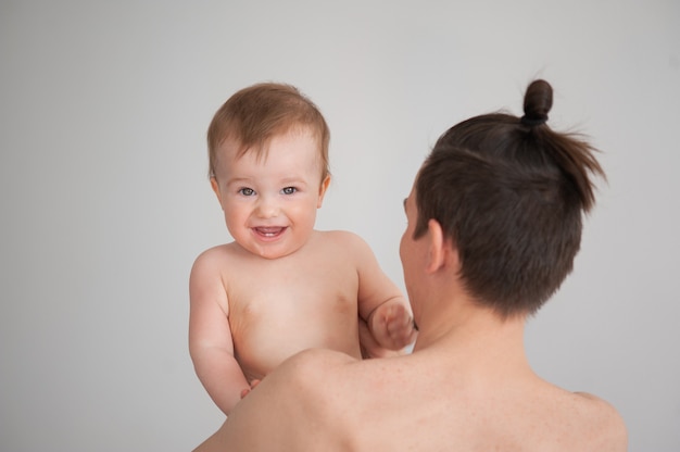 白い背景の上の彼の腕の中でかわいい小さな笑顔の赤ちゃんを保持している父