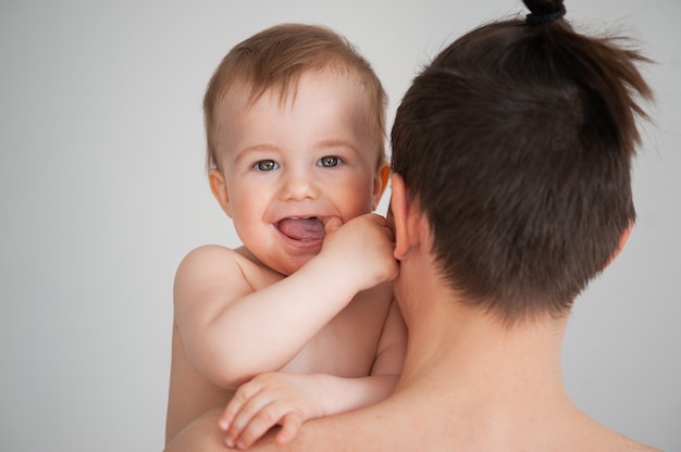 Padre che tiene in braccio un bambino carino e sorridente su uno sfondo bianco