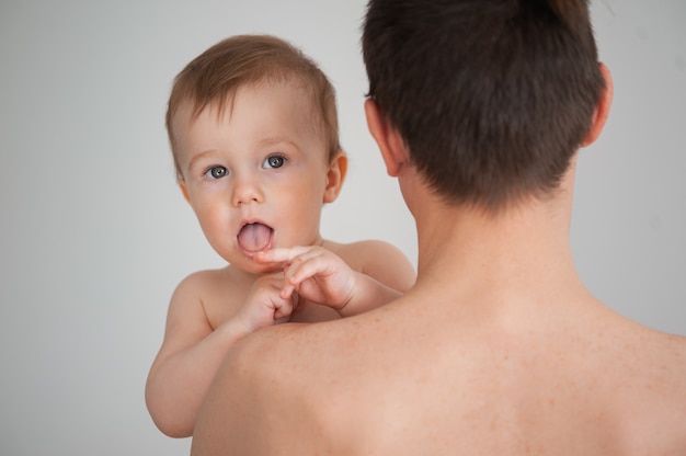 Father holding a cute little smiling baby in his arms on a white background