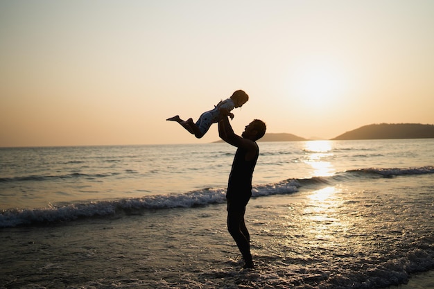 Father holding daughter thrown in the sky at the beach the sea\
at sunset family activities sea trips sandy beaches and\
sunsets