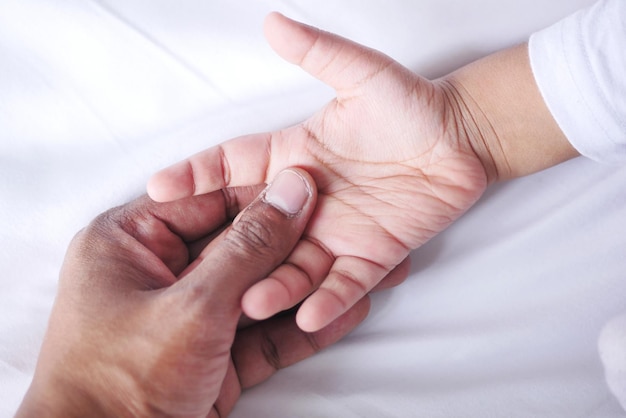 Father holding hand of baby child close up