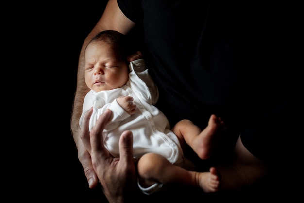 Padre che tiene in mano suo figlio di 15 giorni su sfondo nero