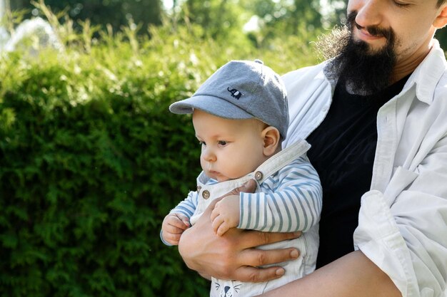 father holding his son in his arms on a background of greenery