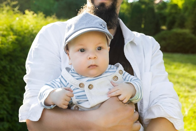 father holding his son in his arms on a background of greenery