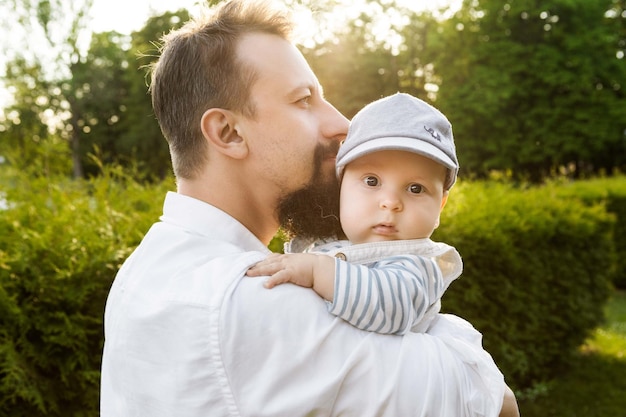 Photo father holding his son in his arms on a background of greenery