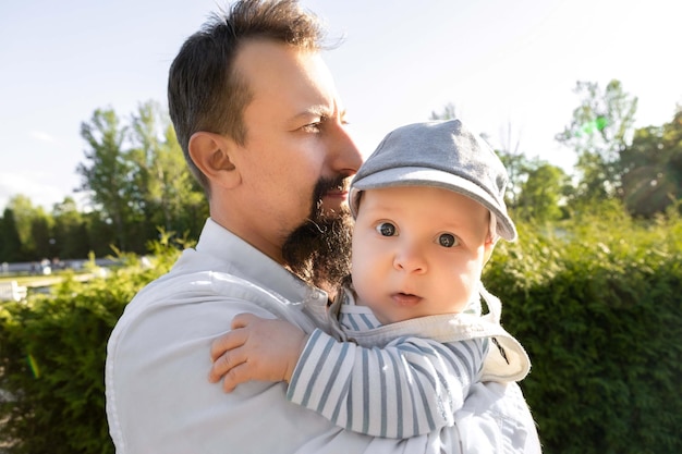 father holding his son in his arms on a background of greenery